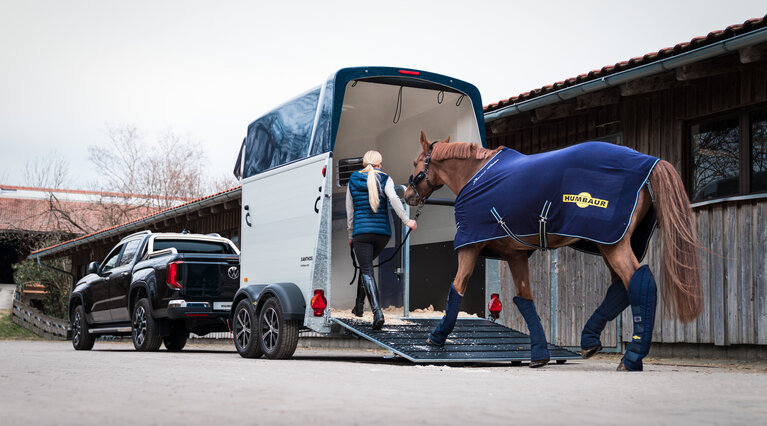 A lady leads her horse into the Equitos Alu