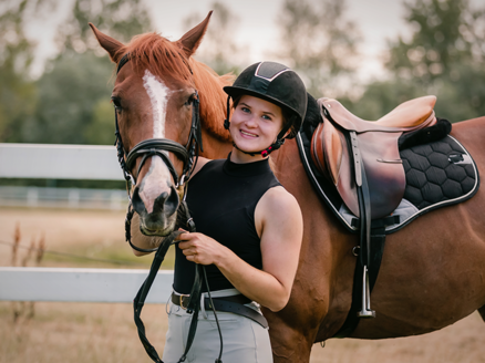 Cavalière souriante avec un cheval sellé