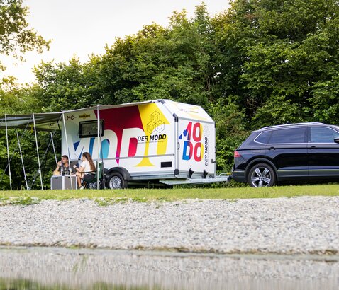 Humbaur MODO camping | © Humbaur GmbH MODO camping trailer with camping accessories on a meadow by the lake. | © Humbaur GmbH